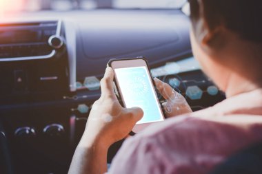 Bir arabanın içinde akıllı telefon tutan kişi, bağlantı, otomasyon ve veri yönetimi için holografik simgelerle gelecekçi bir akıllı teknoloji arayüzü sergiliyor..