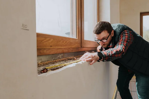 Carpenter measuring window ledge in new house