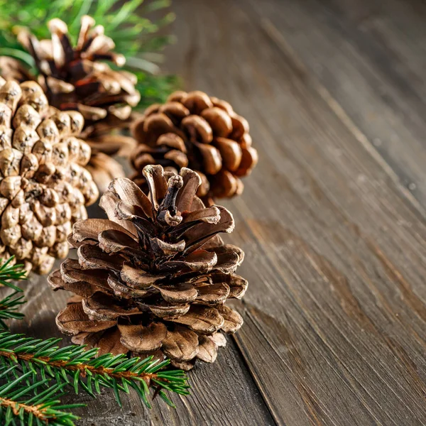 Pine cone and green branch on wooden table with snow, copy space for text.Pine cones on wooden background.