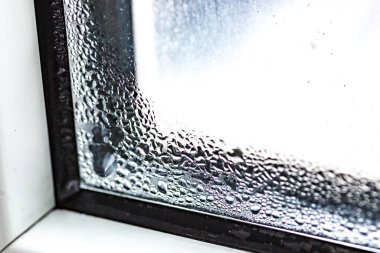 Su yoğunlaşması pencere camlarının üzerine düşer. Standart olmayan metal-plastik bir pencerenin üzerinde yoğunlaştırıcı ve siyah küf damlaları. Konsept: sıcaklık farkı, soğutma, nemlendirme. Plastik. Ekoloji
