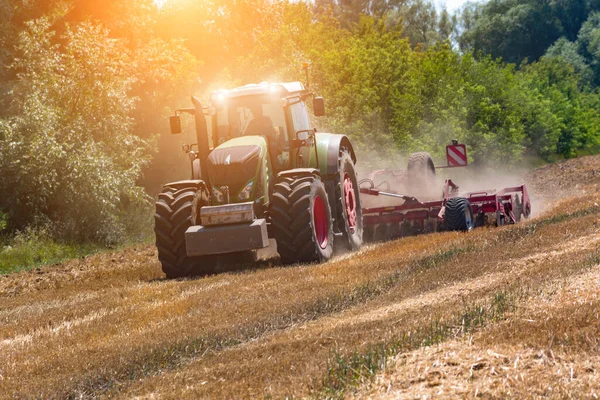 現代の農業用トラクターは 小麦の収穫後に農地を栽培しています 緑のトラクターは土地を働かせます 収穫期 — ストック写真