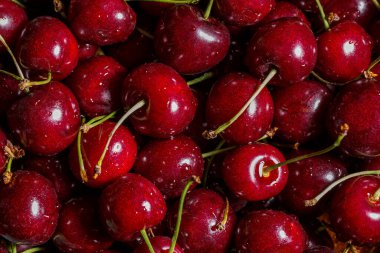 Kiraz rengi arka plan. Yukarıdan çekilen parlak kırmızı kirazlara yakın çekim. Damlalı kiraz. Gıda arkaplanı.