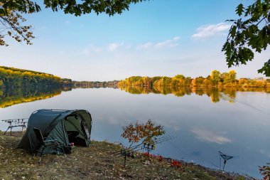 Gölde balık avı. Şafak vakti göle bakan sazan balığı avı manzarası. Balık maceraları, sazan balıkçılığı..
