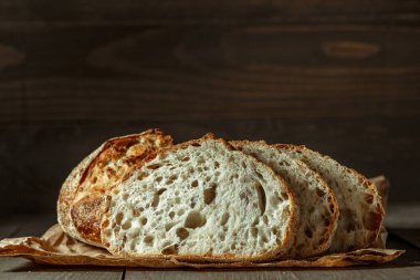 Ekmek, kırsal ahşap arka planda dilimlenmiş geleneksel ekşi ekmek. Geleneksel mayalanmış ekmek pişirme yöntemleri kavramı. Sağlıklı yemek..