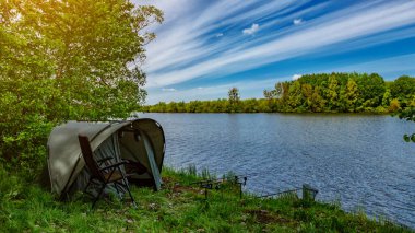 Gölde balık avı. Sazan balıkçılığı manzarası göl manzarası ve bulutlu mavi gökyüzü. Balıkçılık maceraları, sazan balığı avcılığı..