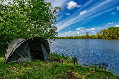 Gölde balık avı. Sazan balıkçılığı manzarası göl manzarası ve bulutlu mavi gökyüzü. Balıkçılık maceraları, sazan balığı avcılığı..