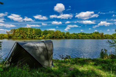 Gölde balık avı. Sazan balıkçılığı manzarası göl manzarası ve bulutlu mavi gökyüzü. Balıkçılık maceraları, sazan balığı avcılığı..