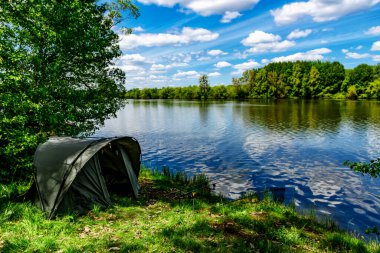 Gölde balık avı. Sazan balıkçılığı manzarası göl manzarası ve bulutlu mavi gökyüzü. Balıkçılık maceraları, sazan balığı avcılığı..