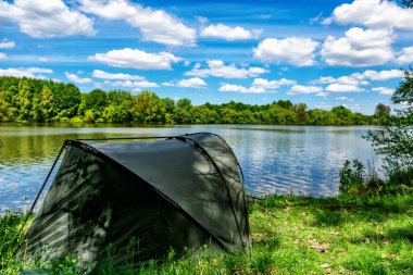 Gölde balık avı. Sazan balıkçılığı manzarası göl manzarası ve bulutlu mavi gökyüzü. Balıkçılık maceraları, sazan balığı avcılığı..