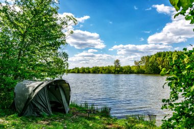 Gölde balık avı. Sazan balıkçılığı manzarası göl manzarası ve bulutlu mavi gökyüzü. Balıkçılık maceraları, sazan balığı avcılığı..