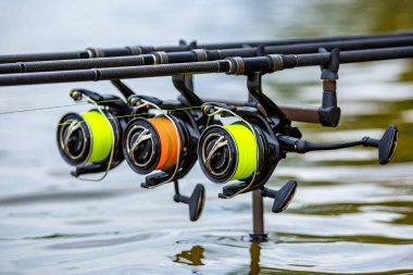 Gölde balık avı. Sazan oltaları özel tripodların üzerinde duruyor. Şafak vakti göle bakan manzaralar..