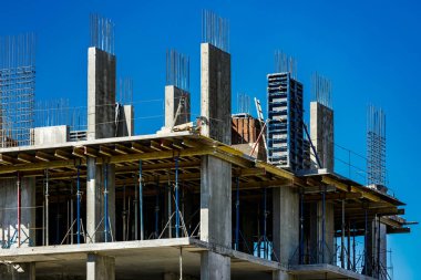 Yeni bir apartman bloğunda çalışma platformları sağlayan kapsamlı yapı iskeleleri, inşaat halindeki uzun binalar, Yeni Bina İnşaat Alanı