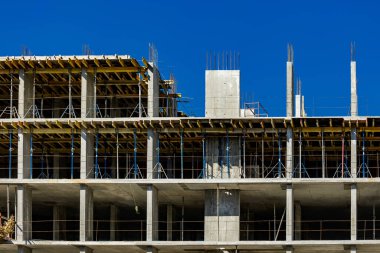 Yeni bir apartman bloğunda çalışma platformları sağlayan kapsamlı yapı iskeleleri, inşaat halindeki uzun binalar, Yeni Bina İnşaat Alanı