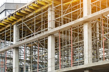 Yeni bir apartman bloğunda çalışma platformları sağlayan kapsamlı yapı iskeleleri, inşaat halindeki uzun binalar, Yeni Bina İnşaat Alanı