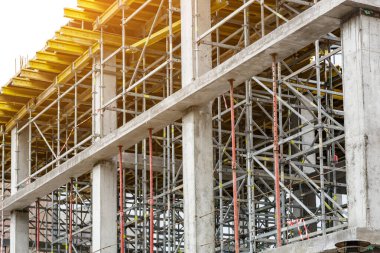 Yeni bir apartman bloğunda çalışma platformları sağlayan kapsamlı yapı iskeleleri, inşaat halindeki uzun binalar, Yeni Bina İnşaat Alanı