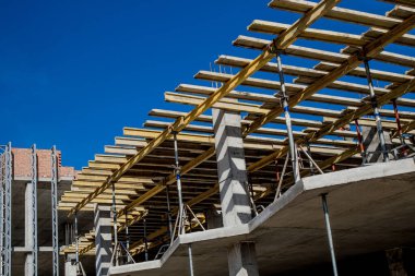 Yeni bir apartman bloğunda çalışma platformları sağlayan kapsamlı yapı iskeleleri, inşaat halindeki uzun binalar, Yeni Bina İnşaat Alanı