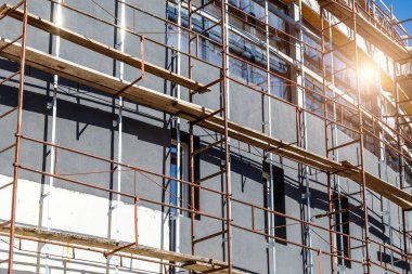 Yeni bir apartman bloğunda çalışma platformları sağlayan kapsamlı yapı iskeleleri, inşaat halindeki uzun binalar, Yeni Bina İnşaat Alanı