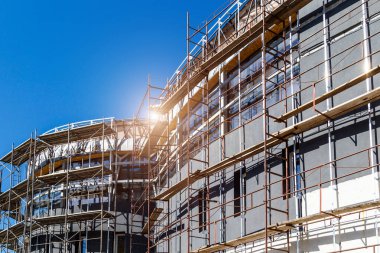 Yeni bir apartman bloğunda çalışma platformları sağlayan kapsamlı yapı iskeleleri, inşaat halindeki uzun binalar, Yeni Bina İnşaat Alanı