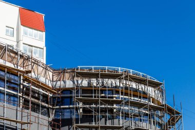 Yeni bir apartman bloğunda çalışma platformları sağlayan kapsamlı yapı iskeleleri, inşaat halindeki uzun binalar, Yeni Bina İnşaat Alanı