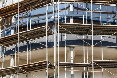 Yeni bir apartman bloğunda çalışma platformları sağlayan kapsamlı yapı iskeleleri, inşaat halindeki uzun binalar, Yeni Bina İnşaat Alanı