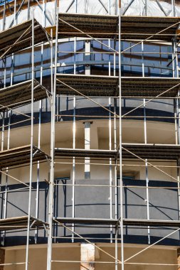 Yeni bir apartman bloğunda çalışma platformları sağlayan kapsamlı yapı iskeleleri, inşaat halindeki uzun binalar, Yeni Bina İnşaat Alanı