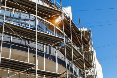 Yeni bir apartman bloğunda çalışma platformları sağlayan kapsamlı yapı iskeleleri, inşaat halindeki uzun binalar, Yeni Bina İnşaat Alanı