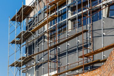 Yeni bir apartman bloğunda çalışma platformları sağlayan kapsamlı yapı iskeleleri, inşaat halindeki uzun binalar, Yeni Bina İnşaat Alanı