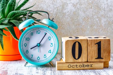 Ahşap takvim, planlama ve yönetim konsepti için tahtadan arka planda alarmlı saat ile birlikte 1 Ekim tarihli tahtadan takvim