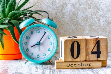 Ahşap takvim, planlama ve yönetim konsepti için 4 Ekim tarihli ahşap takvim ve ahşap arka planda çalar saat.
