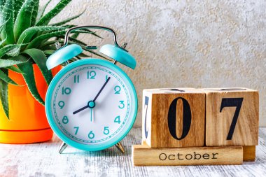 Tahta takvim, planlama ve yönetim konsepti için ahşap arka planda çalar saat ile birlikte 7 Ekim 'de takvime eklenmiştir.