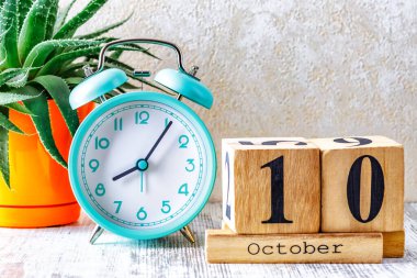 Ahşap takvim, planlama ve yönetim konsepti için 10 Ekim tarihli ahşap takvim ve ahşap arka planda çalar saat.