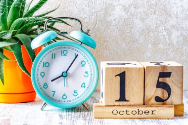 Tahta takvimde 15 Ekim tarihli ahşap takvim. Ahşap zemin üzerinde çalar saat ile planlama ve yönetim konsepti için aylık takvim