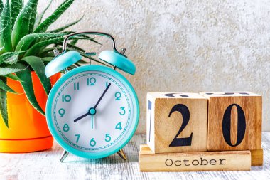20 Ekim tarihli ahşap takvim. Ahşap zemin üzerinde çalar saat ile planlama ve yönetim kavramı için aylık takvim.