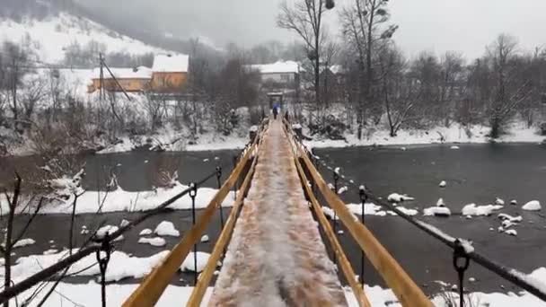冬のカルパチア人 ウクライナのトランスカルパチア村 高齢の女性は ビデオで緊張歩行者橋 霧と寒さにマウンテン川を横断する — ストック動画