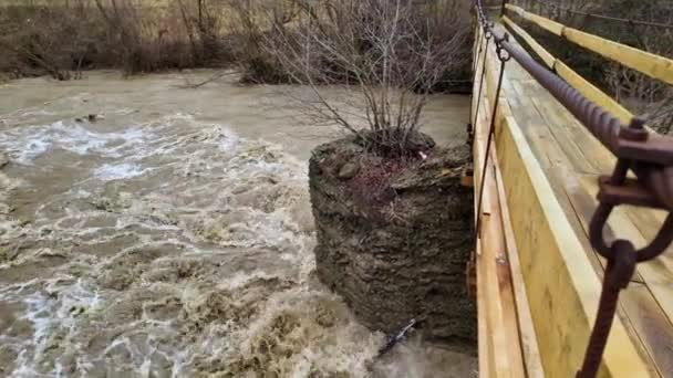 ウクライナ カルパチア トランスカルパシア 雨の後の冬に山で深刻な洪水 大量の水が谷に流れ 吊るされたロープ橋からの脅威の光景 — ストック動画