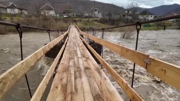 ウクライナ カルパチア トランスカルパシア 雨の後の冬に山で深刻な洪水 大量の水が谷に流れ 吊るされたロープ橋からの脅威の光景 — ストック動画