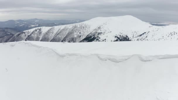 ドローンはカルパティアの頂上を旋回し 雪のトウモロコシで戴冠し アバランスを崩します 尾根の後ろには有名な山岳観光シェルターがあります — ストック動画