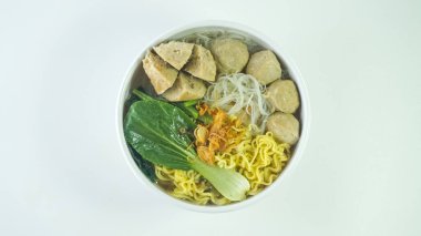 Endonezya 'da Bakso ya da Baso olarak bilinen köfte. Erişte, sebze, biber sosu ve beyaz arka planda elle servis ediliyor. Üst görünüm yatağını kapat