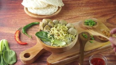 Endonezya 'da Bakso ya da Baso olarak bilinen köfte. Ahşap arka plandaki bir kasede elle erişteli sebze sosuyla servis ediliyor. Üst görünüm yatağını kapat