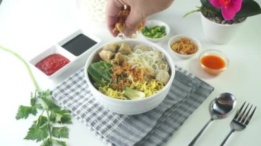 Endonezya 'da Bakso ya da Baso olarak bilinen köfte. Erişte, sebze, biber sosu ve beyaz arka planda elle servis ediliyor. Üst görünüm yatağını kapat