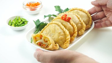 Pastel Goreng olarak bilinen Endonezya 'daki kızarmış pasteller. Kızarmış hamur işi, sebze, tavuk ve haşlanmış yumurtayla birlikte beyaz arka planda, elle servis edilen çiğ biberle servis ediliyor. Kapat.