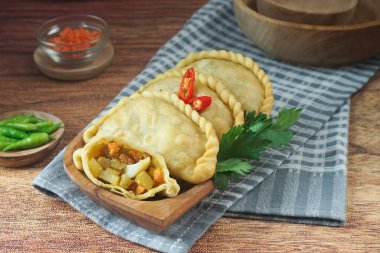 Pastel Goreng olarak bilinen Endonezya 'daki kızarmış pasteller. Ahşap bir tabakta çiğ biberle servis edilen sebze, tavuk ve haşlanmış yumurtayla dolu kızarmış hamur işi. Kapat.