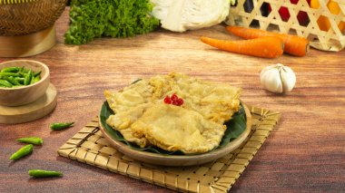 Kızarmış tempeh ya da Tempe goreng, Endonezya 'da yetişen, un hamuru ile kaplanmış, koyu ahşap kaplama bir tabakta servis edilen geleneksel bir yemektir. Kapat.