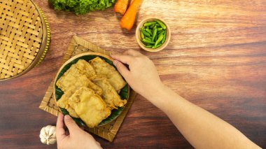 Kızarmış tempeh ya da Tempe goreng, Endonezya 'da elle ahşap bir tabakta servis edilen un hamuru ve baharatlarla kaplı geleneksel bir yemektir. Üst görünüm kopyalama alanı