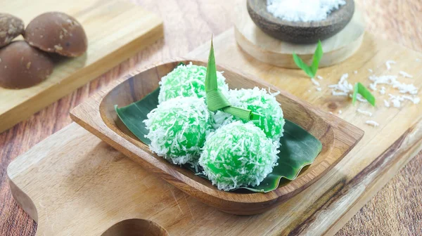 stock image Kelepon cake or klepon is a traditional food from Indonesia made of glutinous rice flour brown sugar grated coconut served in a plate on dark wood background. Close up