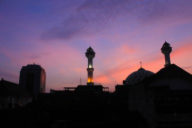 Büyük Bandung Camii 'nin silueti. Turuncu gökyüzü ve arka plan olarak güneşin doğuşu.