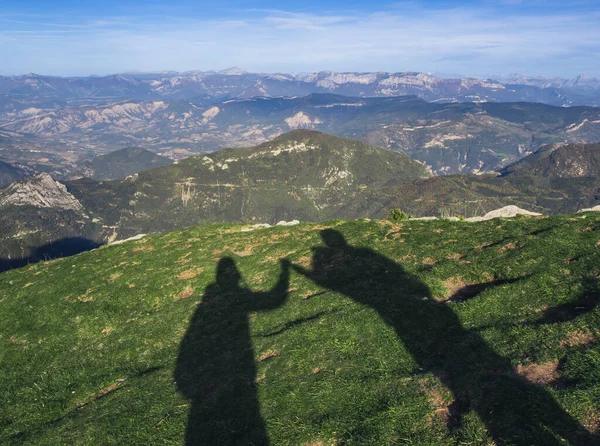 The shadow of a couple in love in the mountains. Cheering reaching the top of the mountain in the alps. Happy people who reached success and a amazing peaks landscape