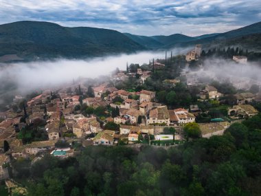 Fransa 'nın Mirmande köyünün panoramik manzarası. Sabahleyin şehrin etrafında yükselen yoğun siste havadan çekilmiş bir fotoğraf.