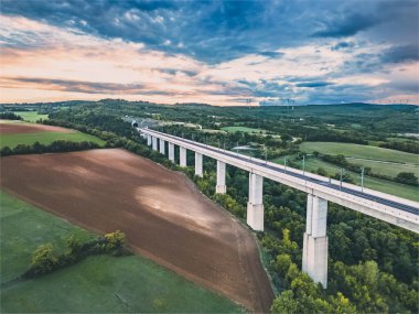 Üstgeçitteki yüksek hızlı trenler için demiryolu hattının havadan görüntüsü. Çevredeki tarlaların, ormanların ve etrafındaki dağların panoramik sonbahar manzarası.
