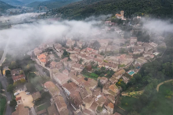 stock image Panoramic view of the old village of Mirmande in France. Aerial photo in the morning in the thick fog rising around the town